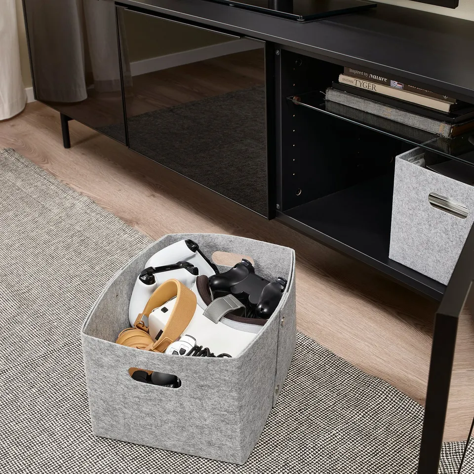 Grey felt storage box holds sandals and gaming controllers, perfect for organising accessories in living rooms or closets.