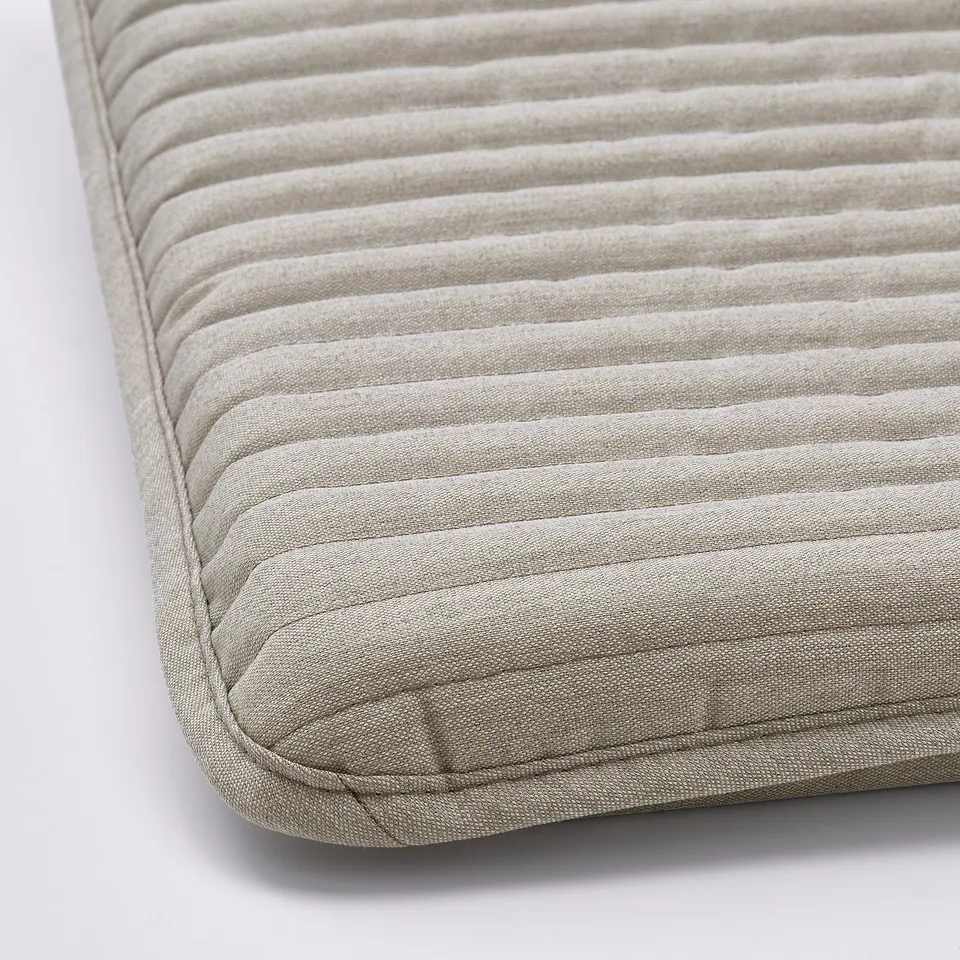 Close-up of a plush, textured footstool cushion with vertical tufted lines, showcasing high-quality fabric.