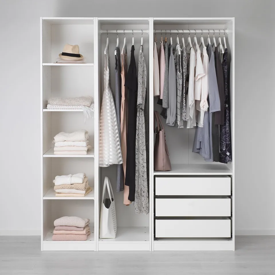 Minimalist wardrobe with clothes, towels, and storage drawers.