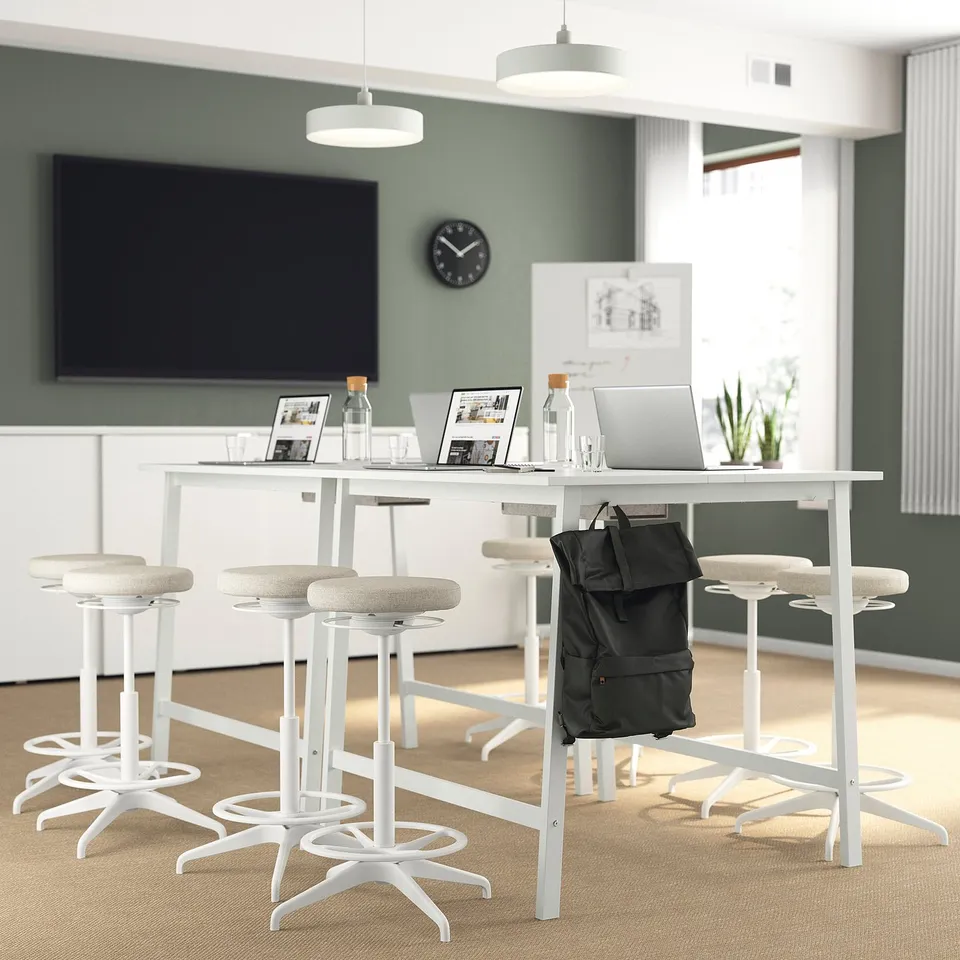 Modern office with MITTZON high tables, laptops, tv, and green walls.