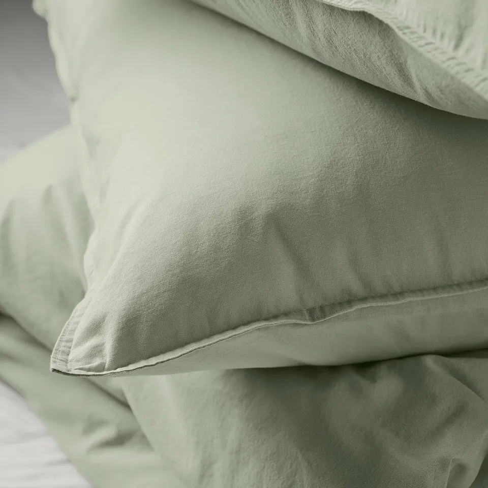 Close-up of soft, green, washed cotton bedding, showcasing its texture and quality.