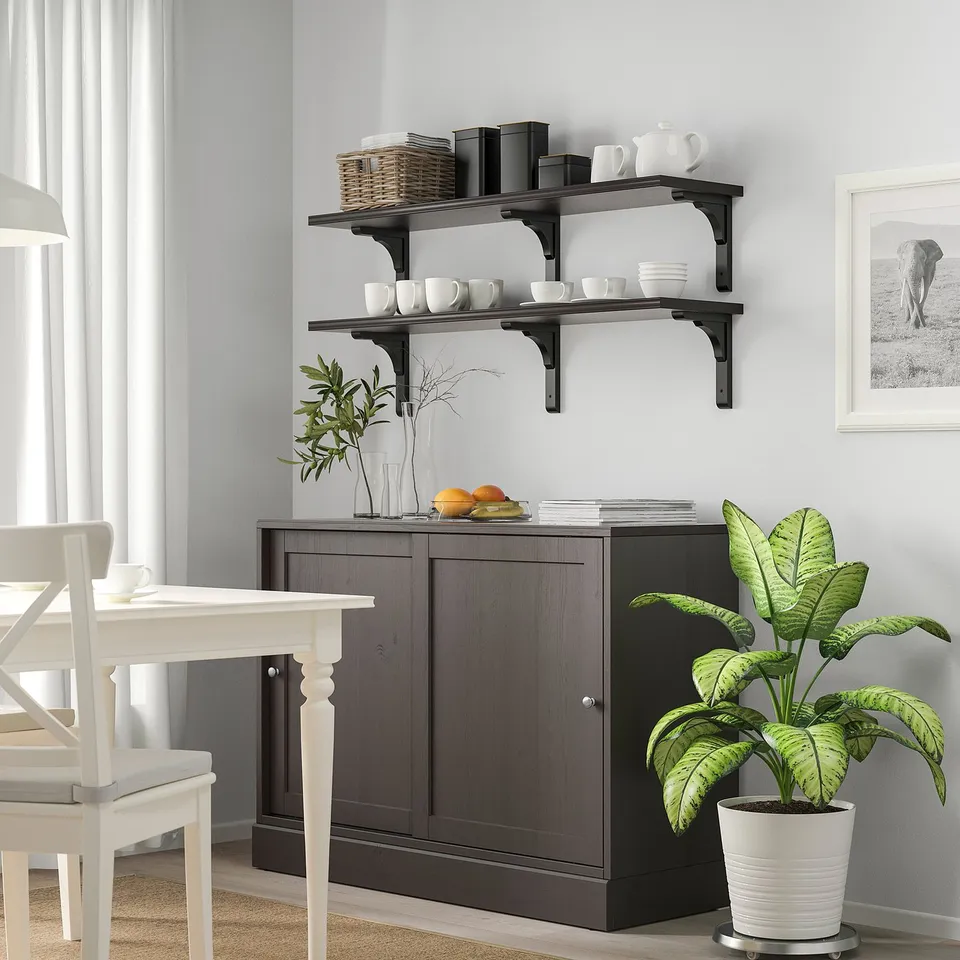 Modern dining room with BERGSHULT shelf, cups, bowls, plant, window curtains.