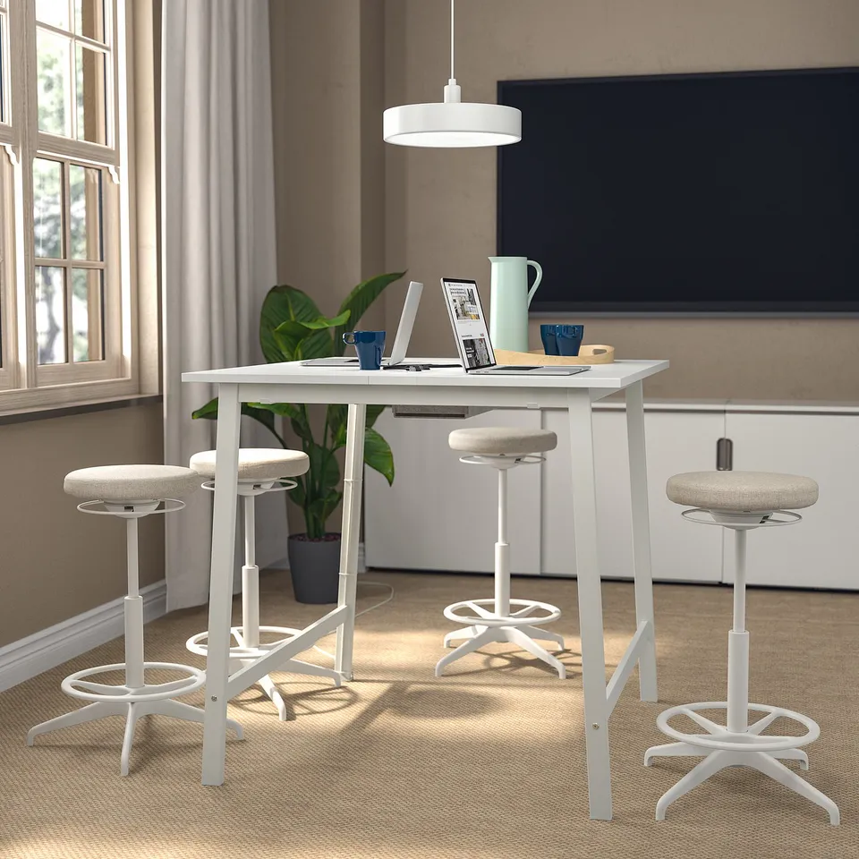 MITTZON meeting table with stools, laptop, cups, plant. Comfortable seating, wall screen, window.