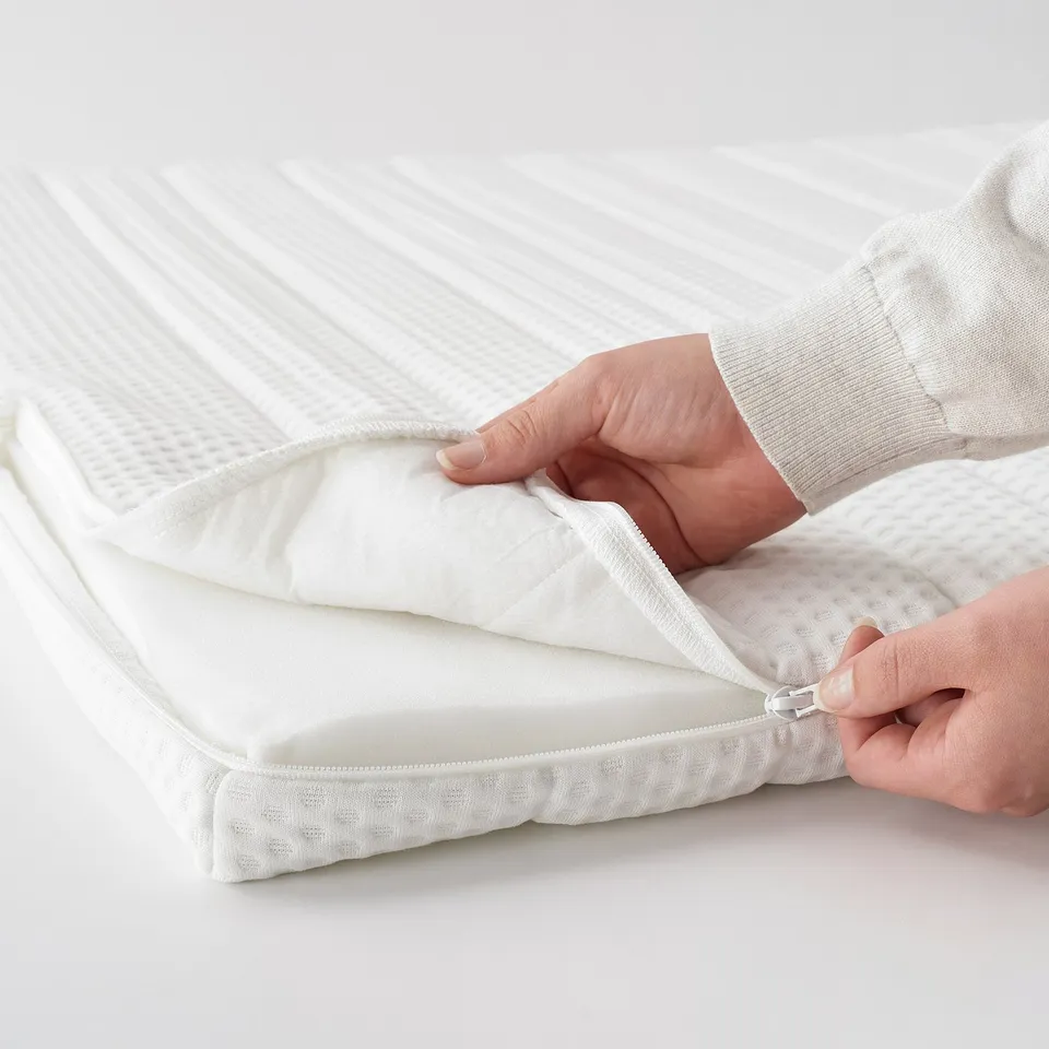 Image shows hands attaching white mattress zip cover, highlighting easy-to-use zip feature.