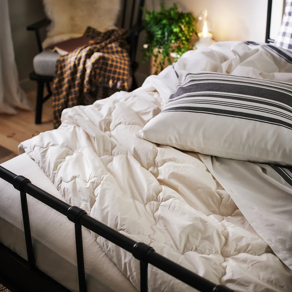 White duvet with grey stripes, 100% cotton, button closure, on bed.