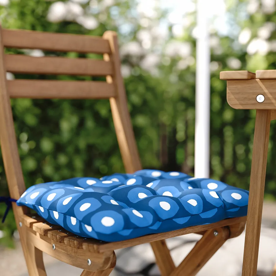 Blue patterned outdoor chair cushion on wooden chair.