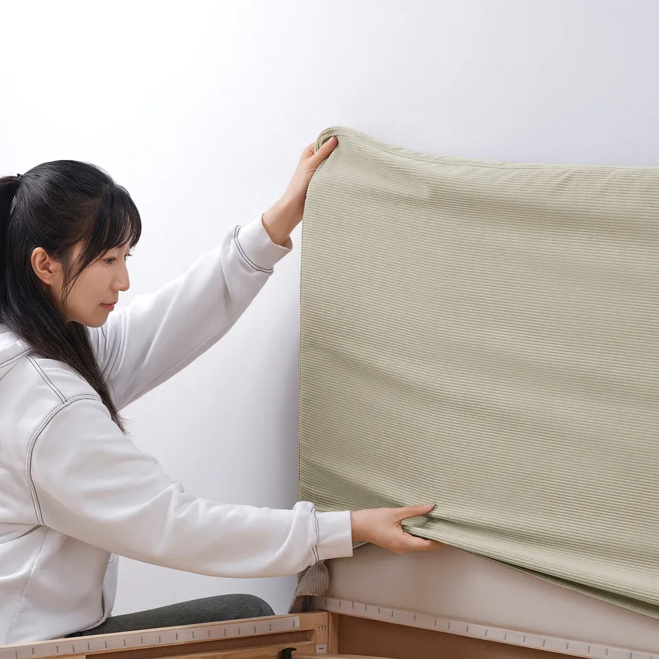 Person attaching TÄRNKULLEN bed cover, showing its easy removal and machine washable feature.