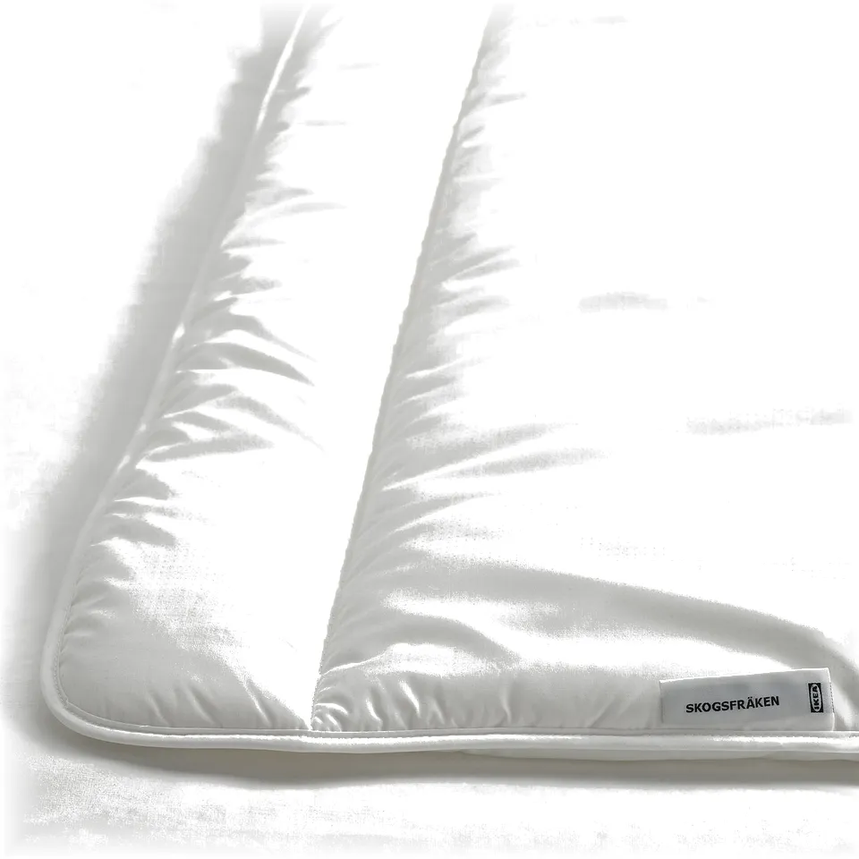 A close-up of a white, fluffy comforter with neat stitching and a tag on one corner, indicating high quality and craftsmanship.