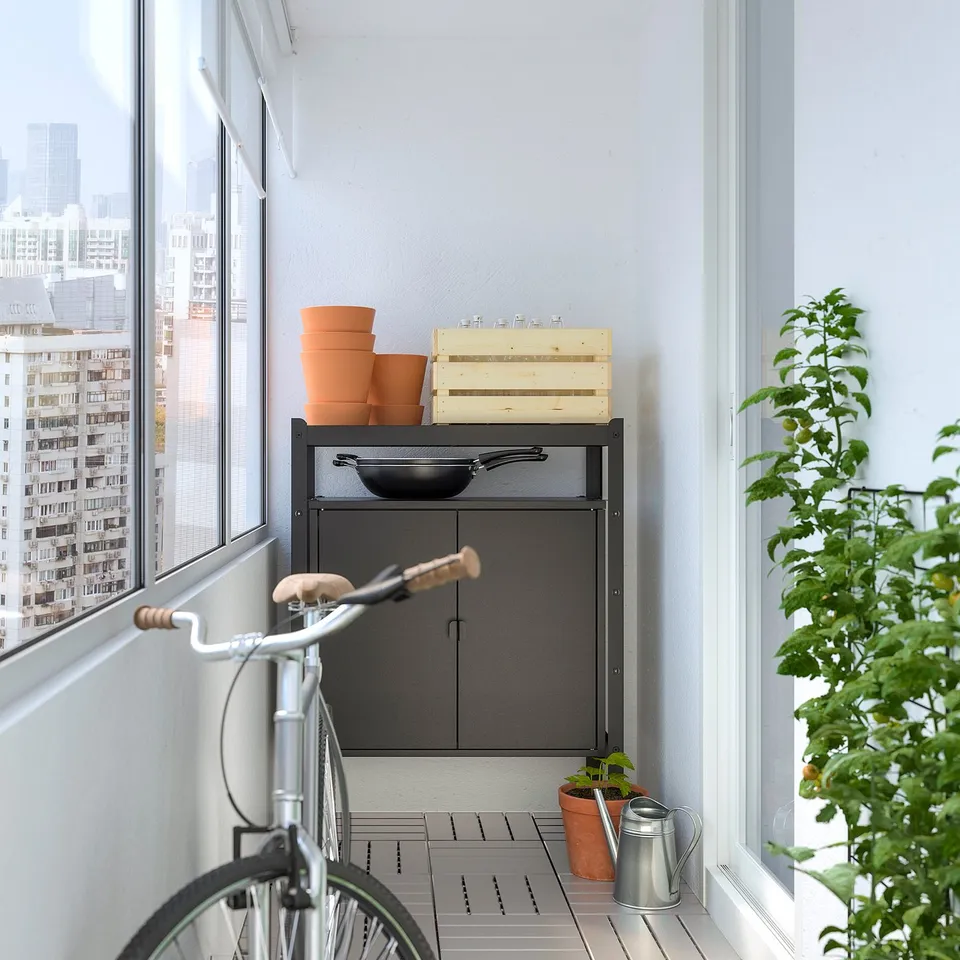 Balcony with BROR cabinet, bike, and potted plant near door.