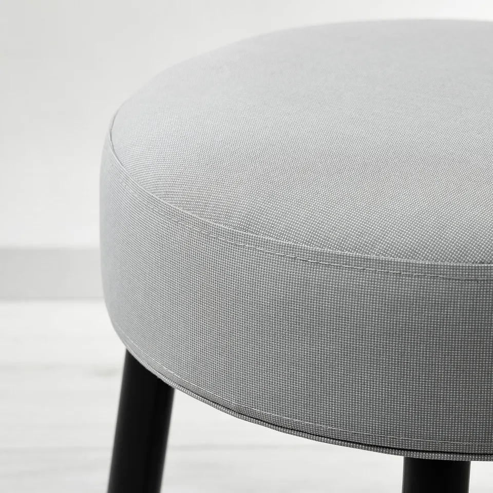 Round upholstered stool with sleek, black metal legs. Modern, minimalist design. Premium fabric.