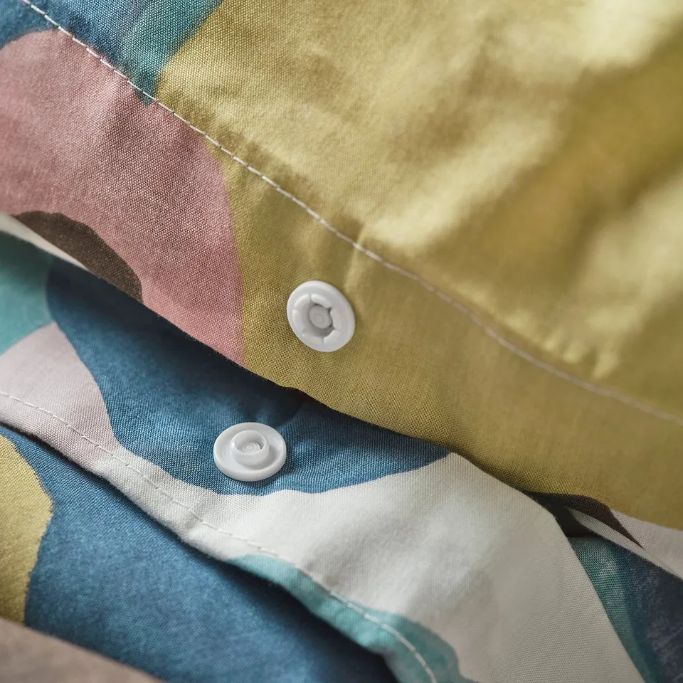 Close-up of VIDEOXBÄR duvet with earthy leaf print, showing secure press studs.