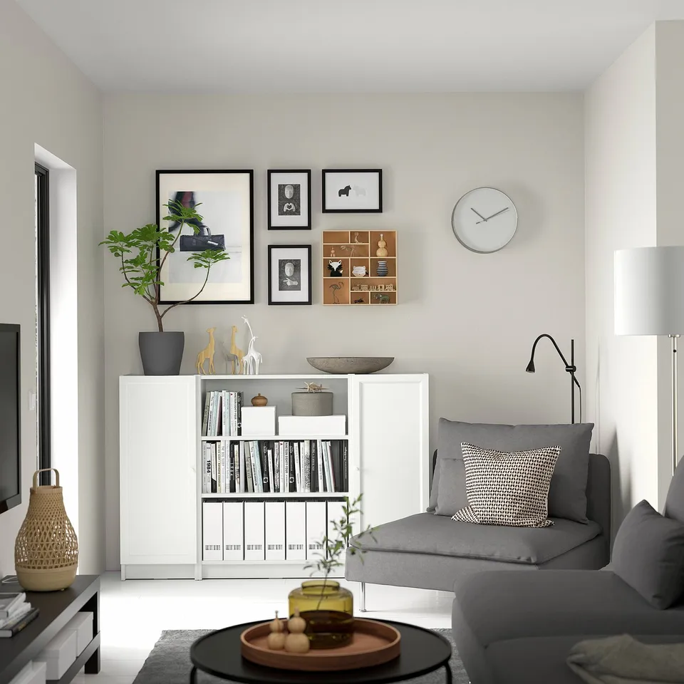 Modern living room with white BILLY bookcase, grey couch, coffee table, and decorative items.
