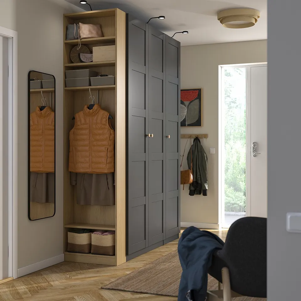 Modern entryway with PAX wardrobe, vest, boxes, rug, and glass door.