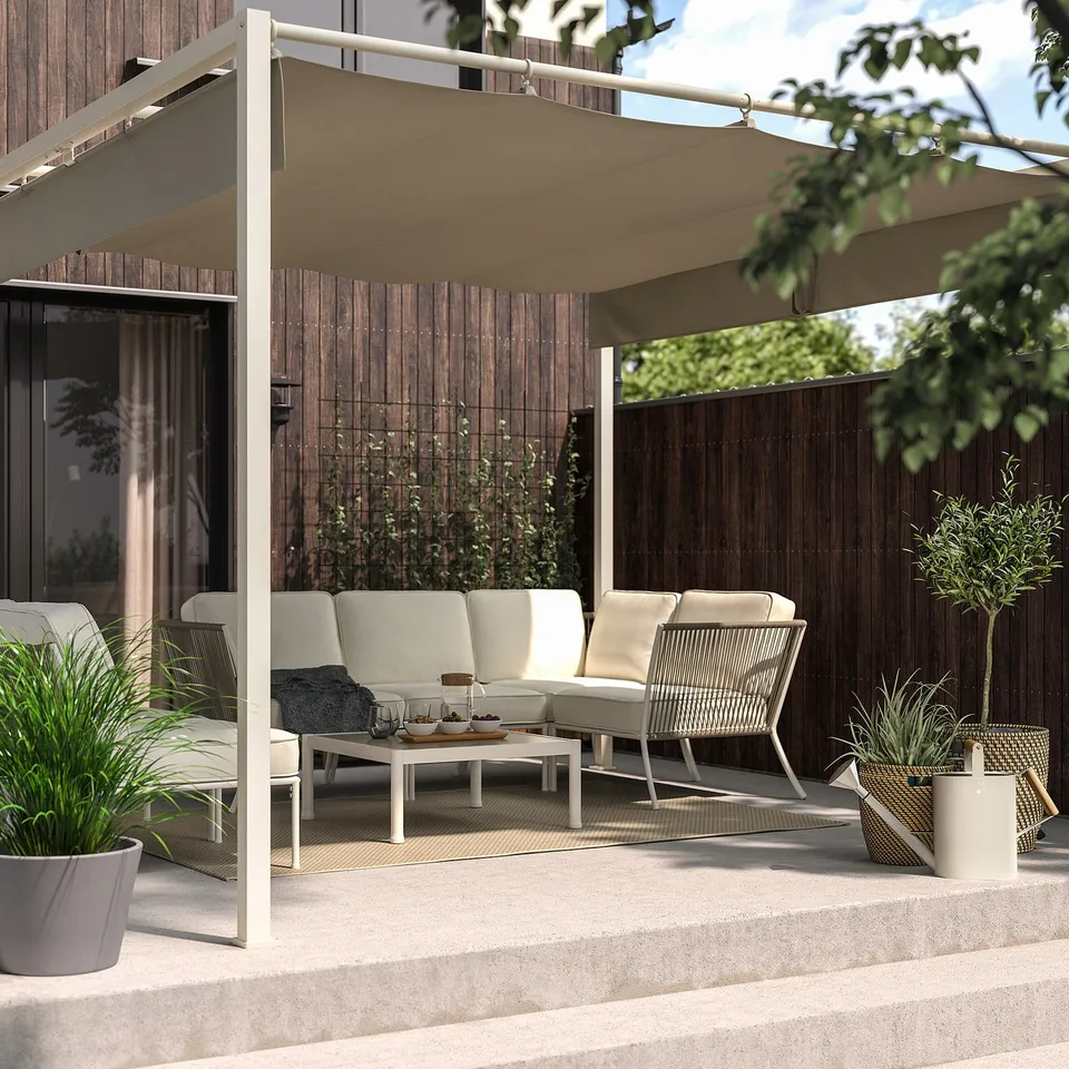 HAMMARÖN beige pergola shades modern patio; includes couch, chairs, and plants.