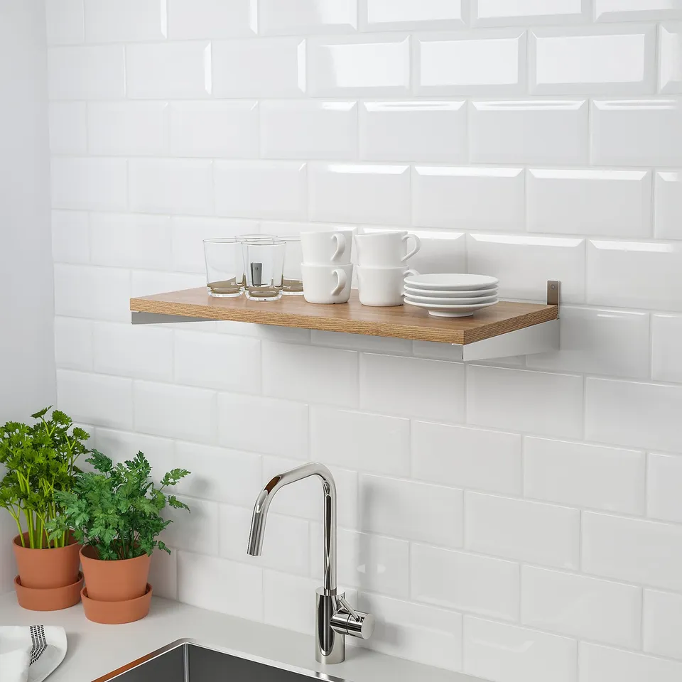 Modern kitchen with wooden shelf on tiled wall, holding mugs, glassware, and plates. Below, a sink with herbs; efficient storage.