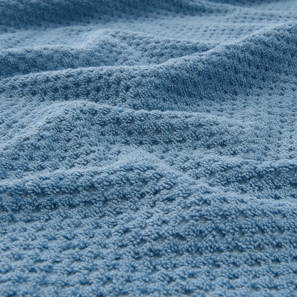 Close-up of soft, fluffy blue towel, showcasing its textured, absorbent weave.