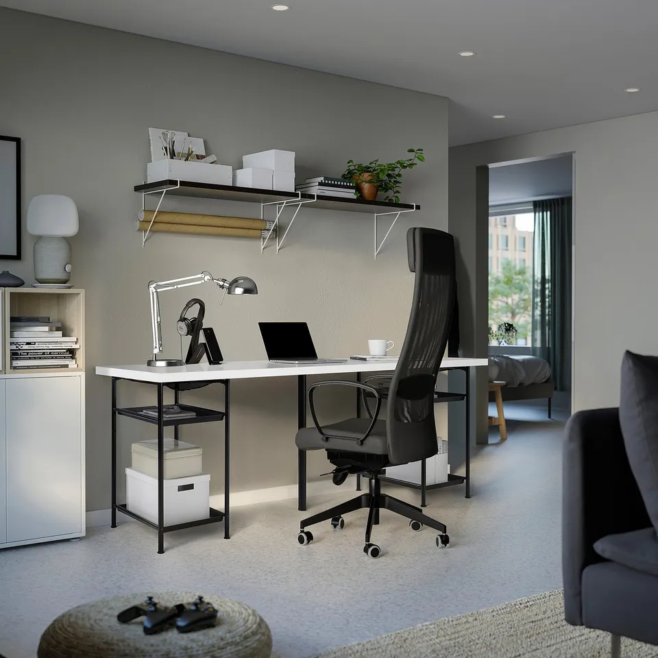 White desk, black chair, side cabinet, wall shelves, grey armchair.