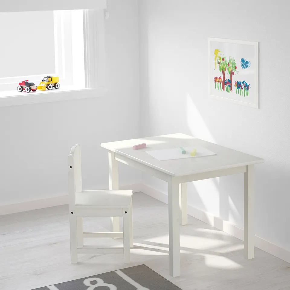 Kids table and chair set with toys and art print.