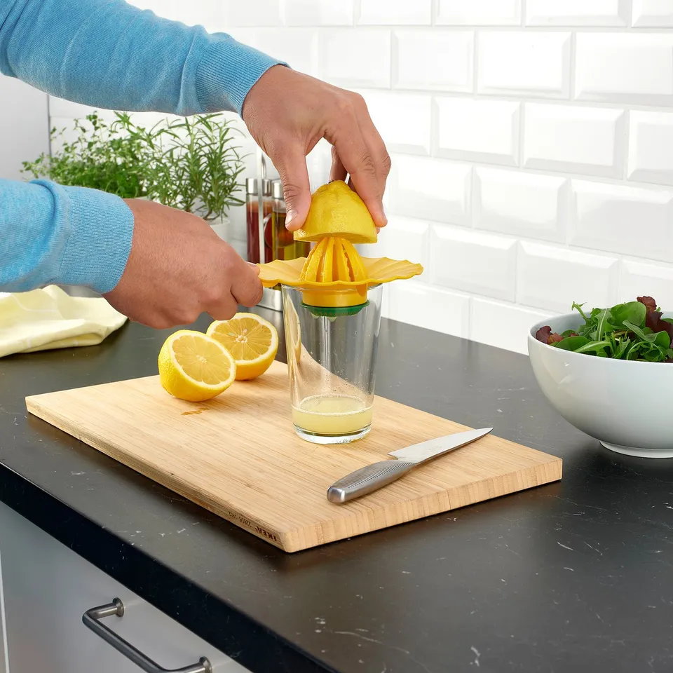 Person squeezing lemon using UPPFYLLD juicer, capturing fresh juice in glass.