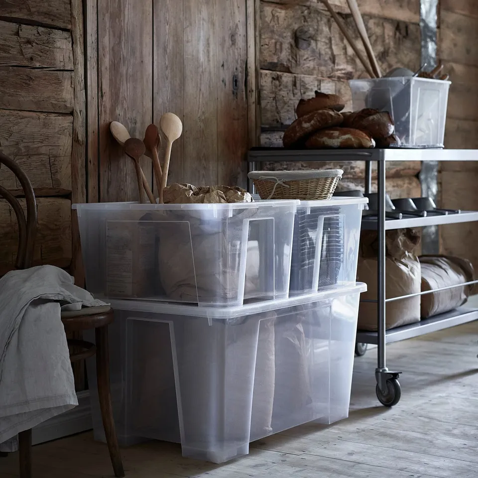 Plastic storage bins on wheels, filled with items, arranged in a rustic wooden room.