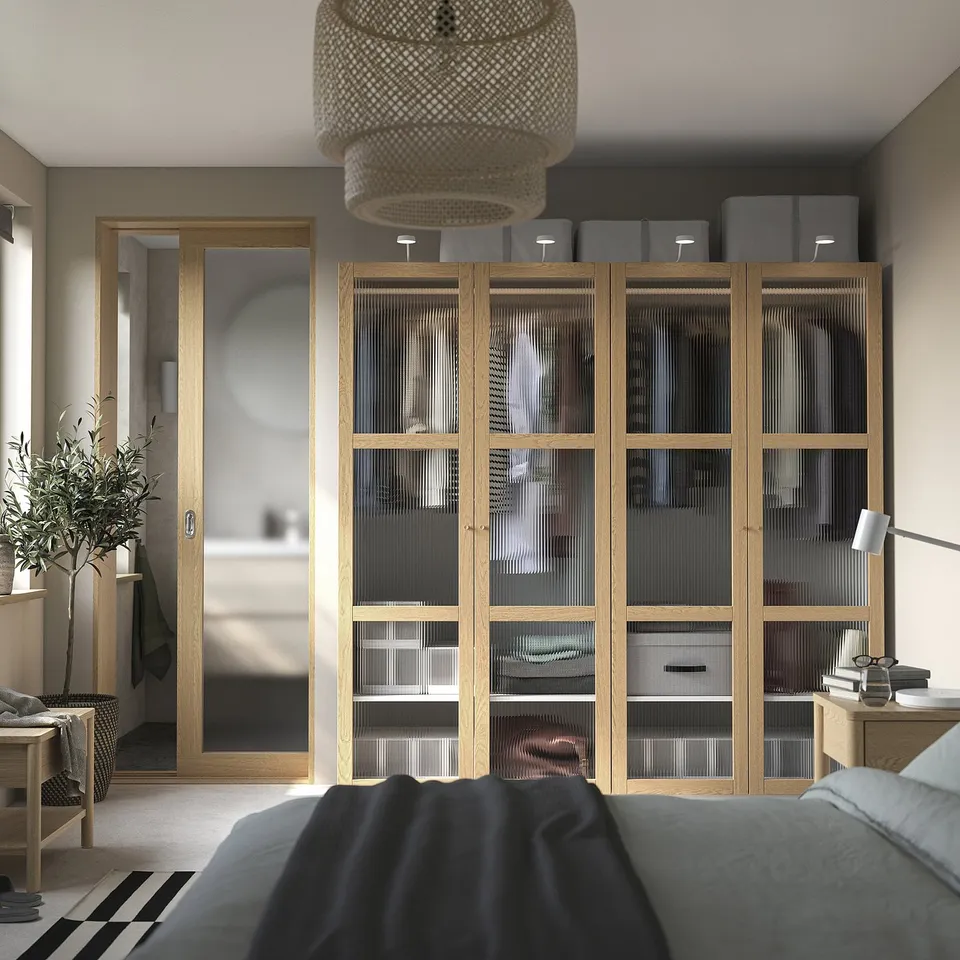 Modern oak bedroom with TONSTAD wardrobe, glass doors, lighting, & matching furniture in soft grey & black.
