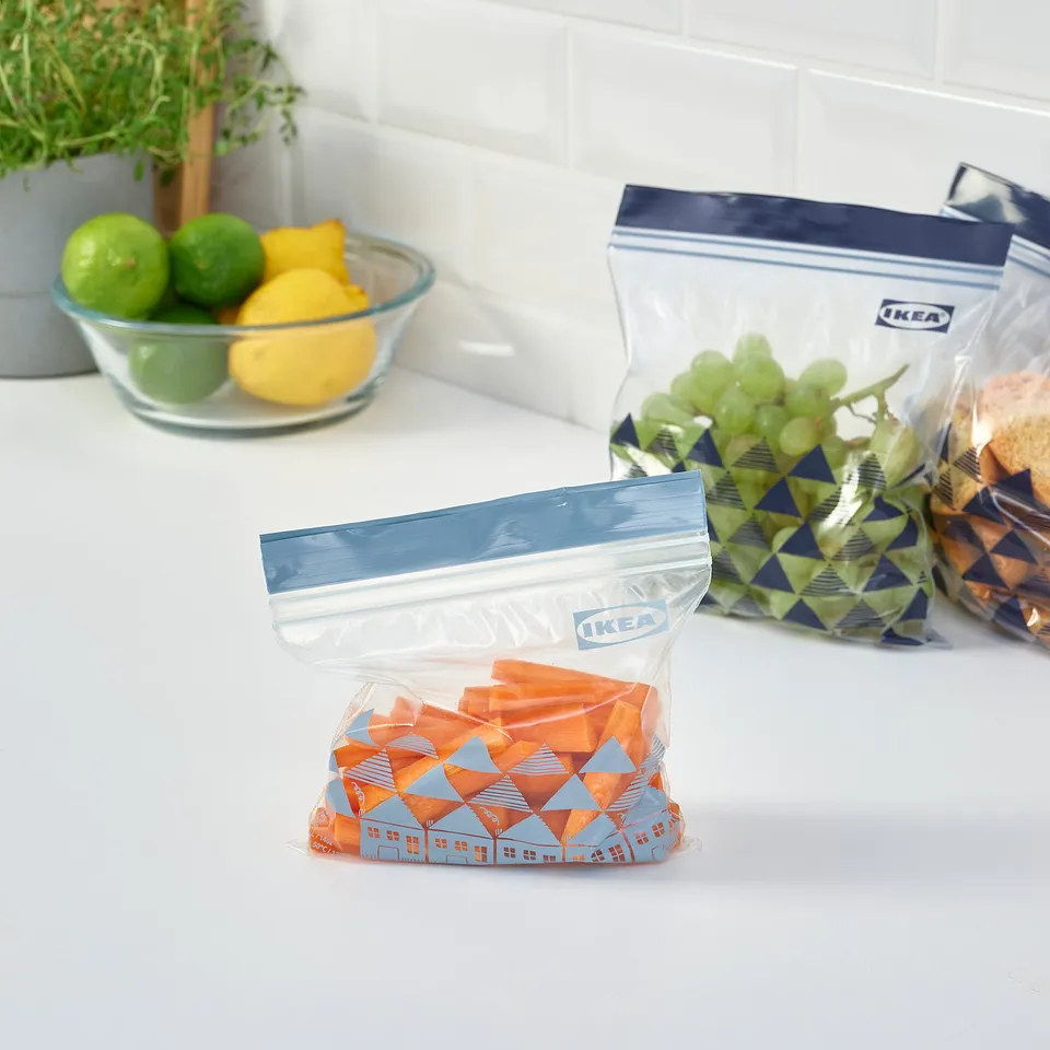 Three resealable bags by IKEA labelled ISTAD holding fruits and snacks, organised on a kitchen counter.