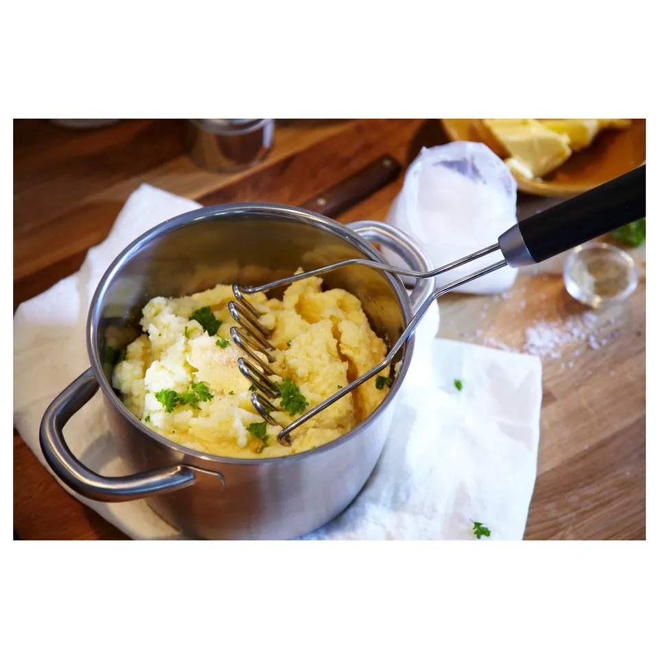 Metal saucepan with mashed food and utensil, resting on cloth