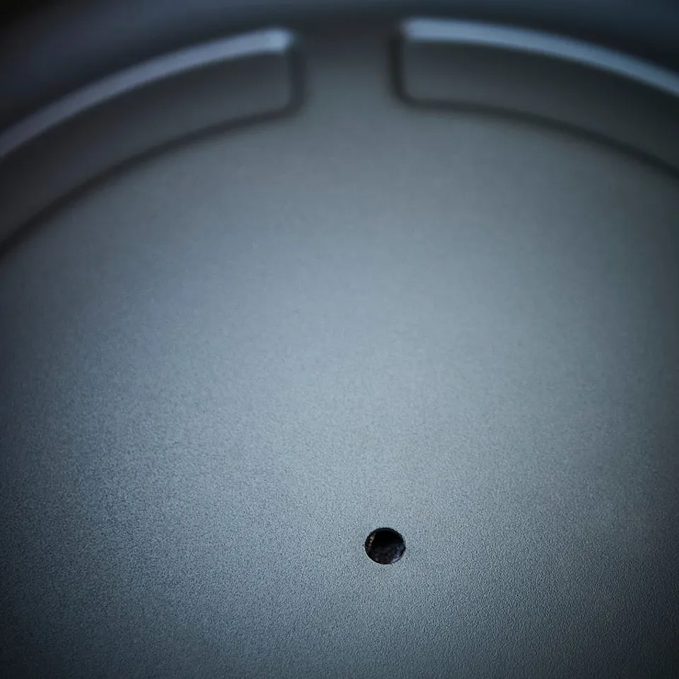 Dark grey metallic pot with smooth surface and drainage hole, soft curved edges.