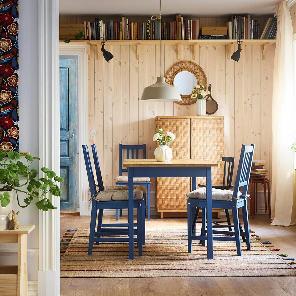 Cosy dining area with blue PINNTORP wooden chairs & table, warm & traditional.
