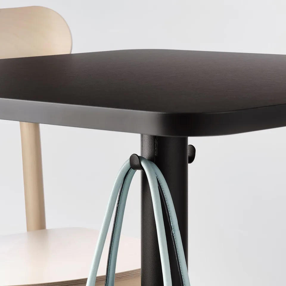 Black and light wood chair with teal metal legs. The legs have a unique curved design for stability.