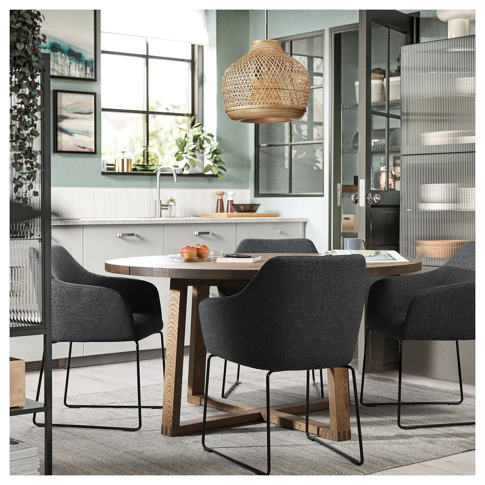 Modern dining set with grey upholstered chairs, wooden table, and wicker pendant light.
