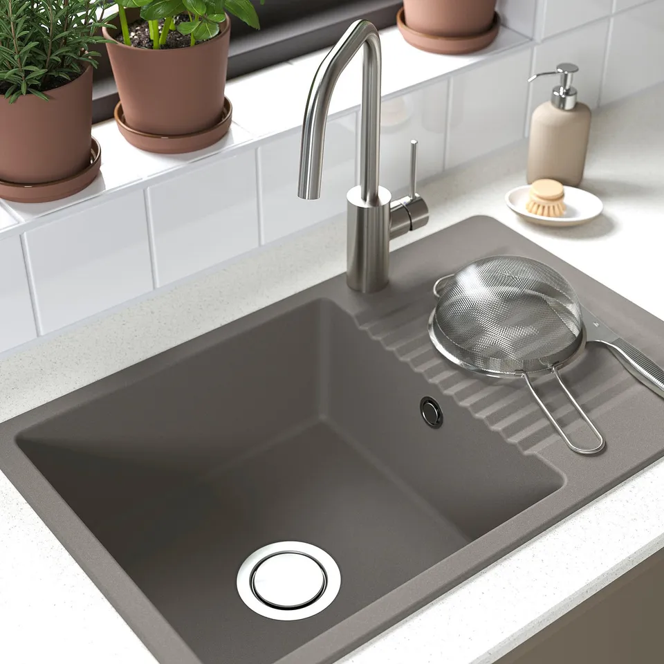 Dark grey composite sink with modern tap, strainer, and potted plants.