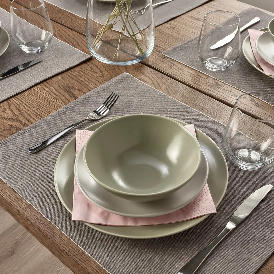 Pretty table setting with grey and green plates, pink napkins, silverware, and clear glass cups; elegant and organised.
