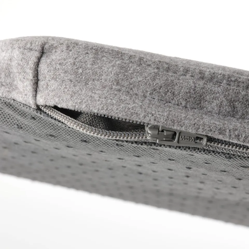 Close-up of modern chair pad with recycled materials, silver zip, and textured underside.