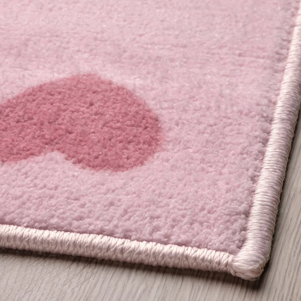 Close-up of soft, plush pink rug with heart pattern, made from recycled materials.