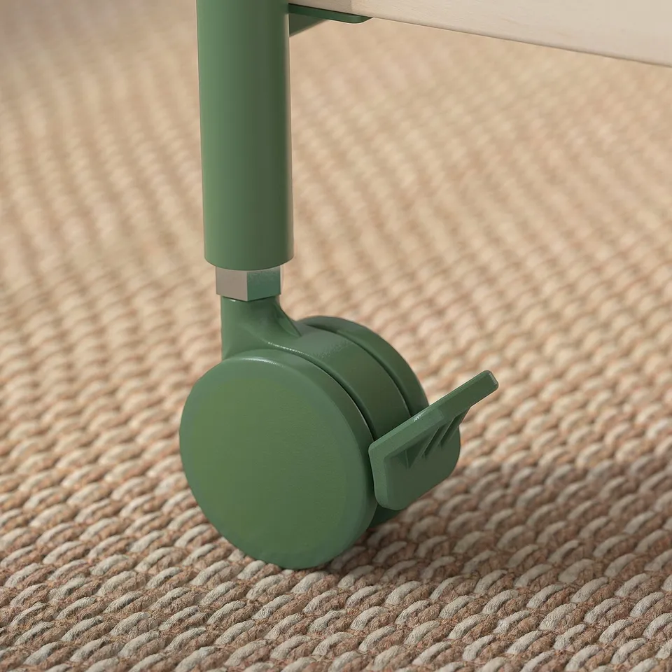 Close-up of a cabinets green castor wheel on woven beige carpet. Quality design with smooth, lockable caster for easy mobility.
