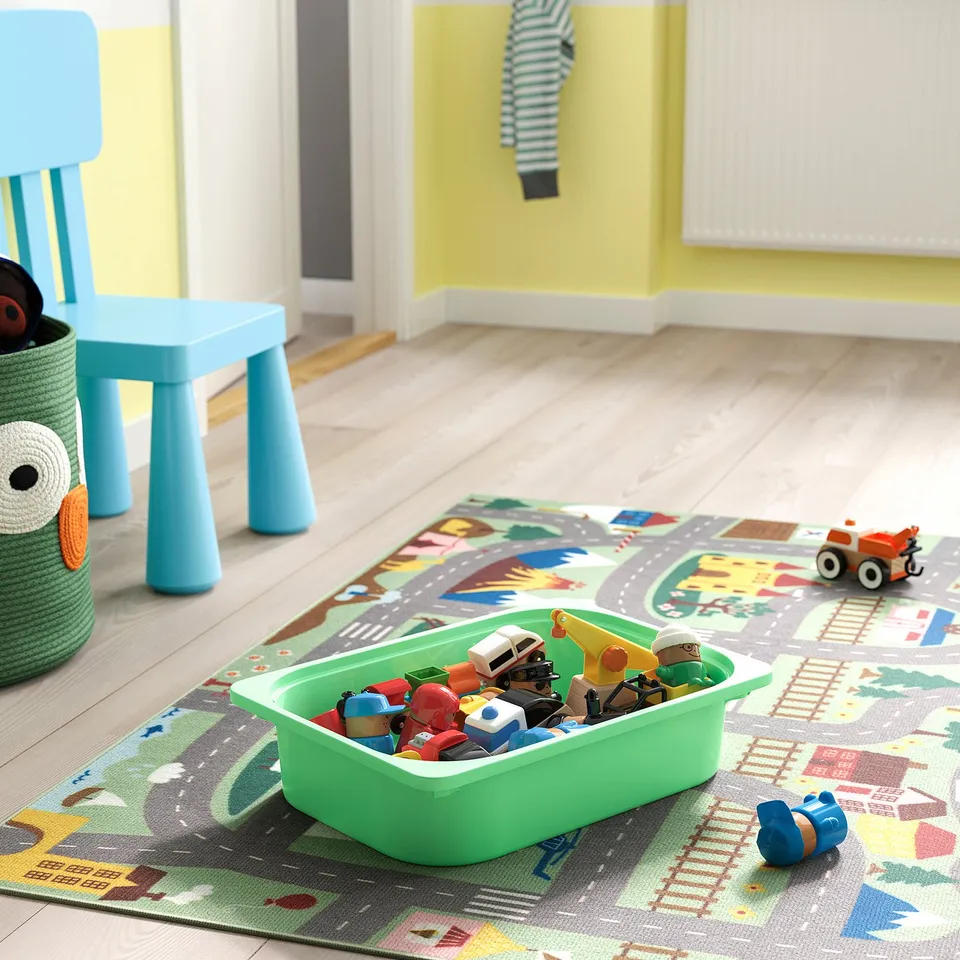 Kids room with colourful TROFAST storage: blue chair, toys in green bin on playmat.