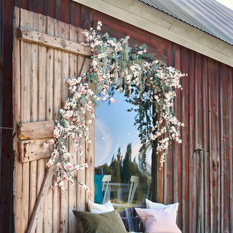 Barn with rustic door, flowers, and hay bales with cushions.