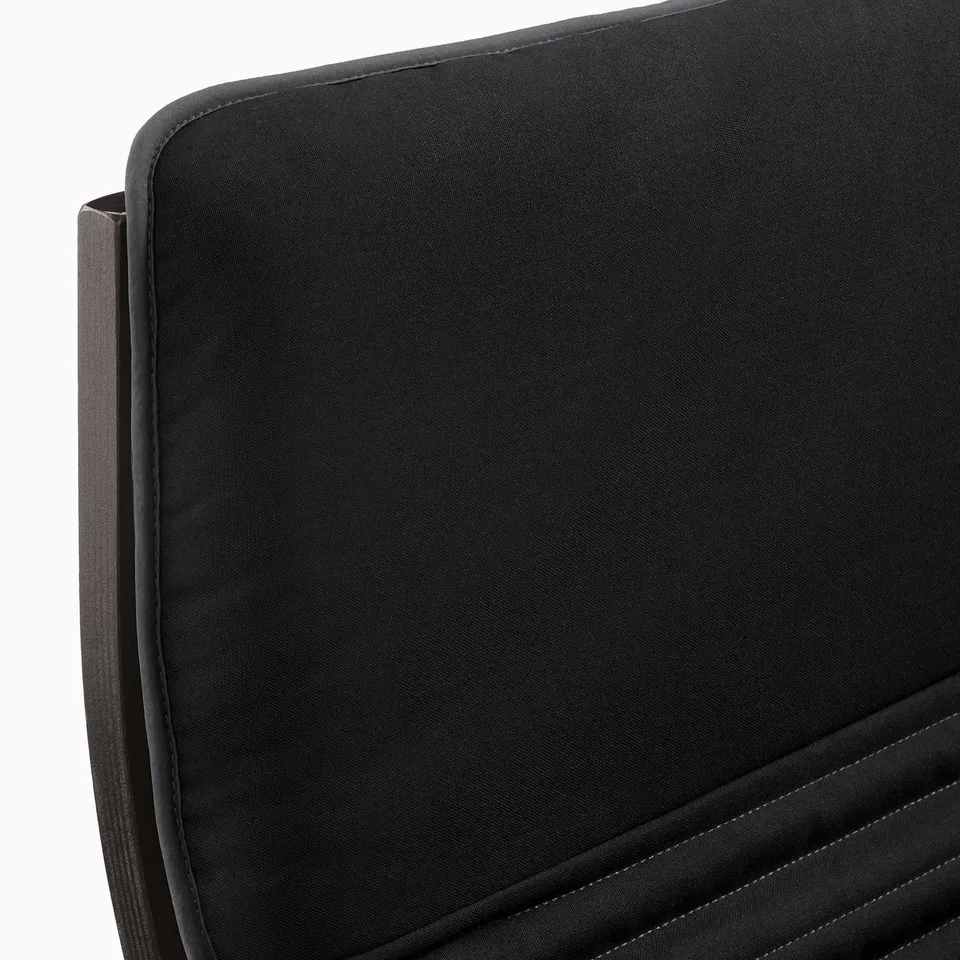 Black armchair cushion detail. Shows smooth, high-quality fabric and neat stitching.