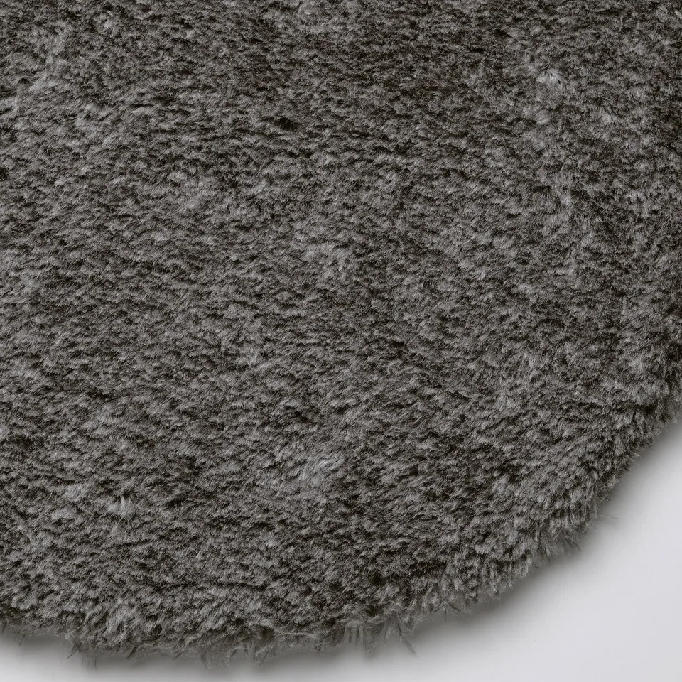 Close-up of a soft, fluffy, grey circular rug. The texture appears luxurious and inviting.