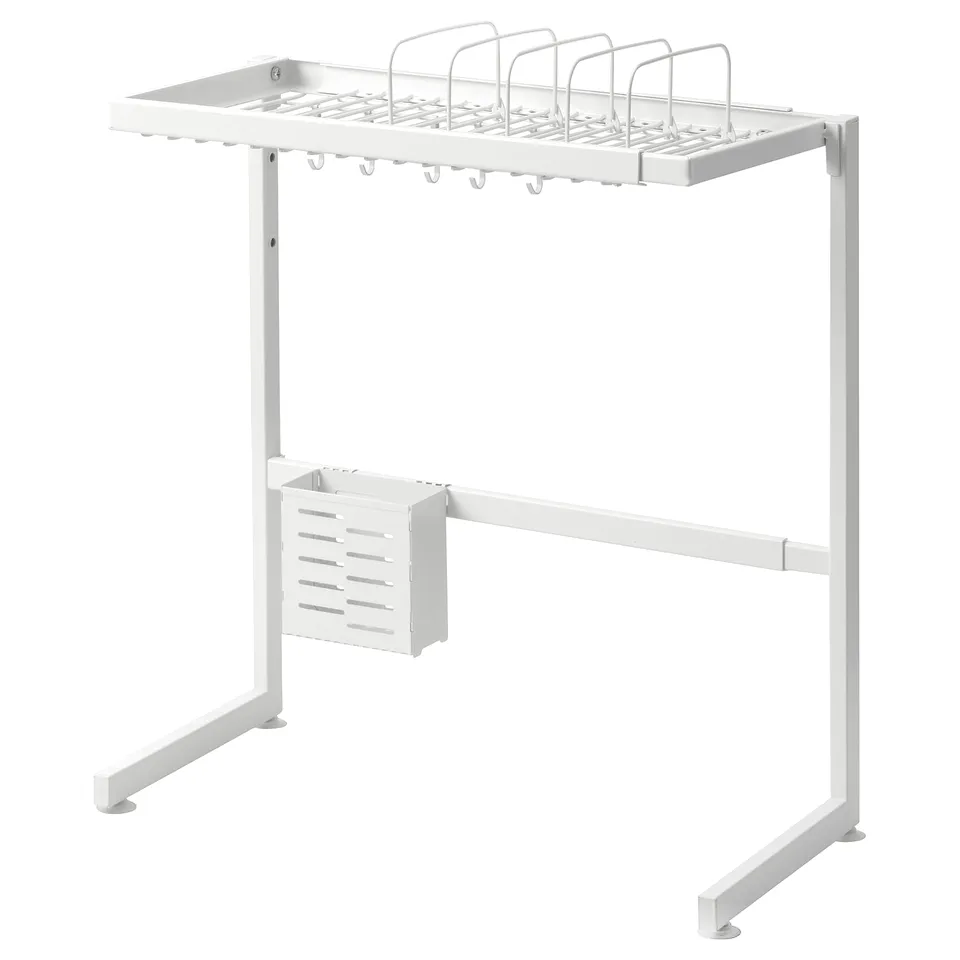 A white SKYGGFISK dish rack standing over a sink. Its made of metal with plastic feet, holding dishes, utensils, and cutlery.