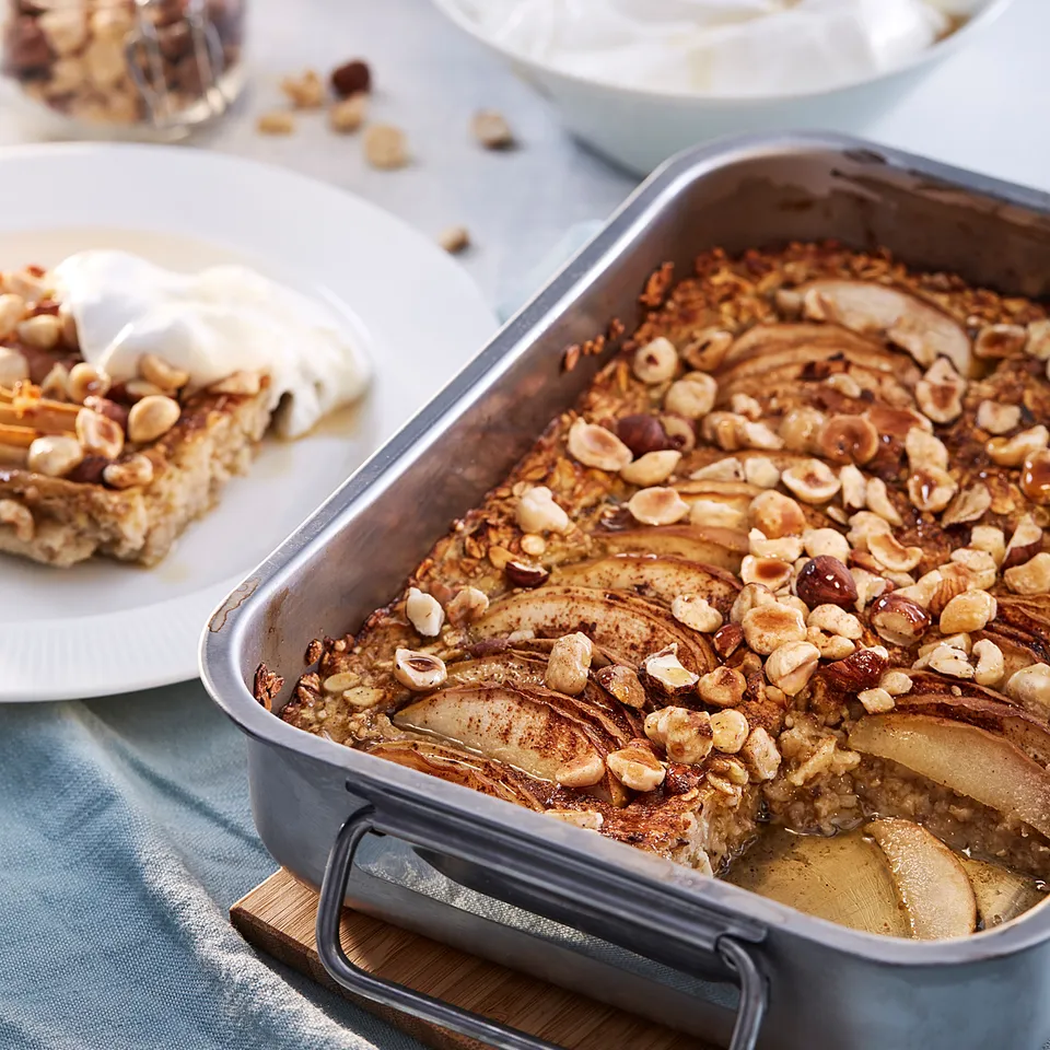 Dessert display with apple pie, whipped cream, hazelnuts, and a slice served on a plate.