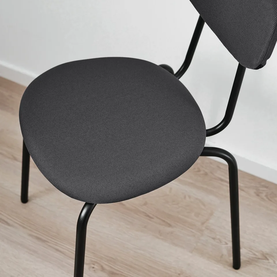 Modern black chair with round cushion and metal legs on wooden floor.