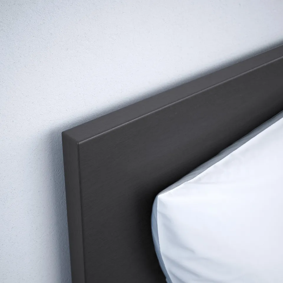 Close-up of a dark wooden headboard against a light wall, showcasing smooth finish and sturdy construction.