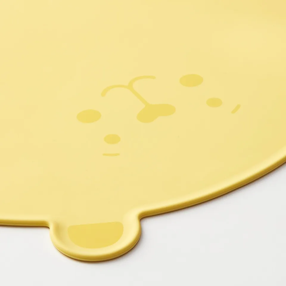 Yellow silicone placemat with raised edges and loop, designed for child mealtime, with vivid colour and sturdy form.