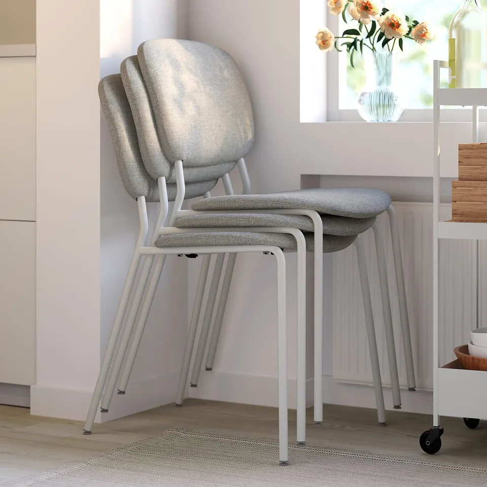 Stackable modern dining chairs with padded seats and backs, suitable for indoor use, shown neatly stacked in a corner.