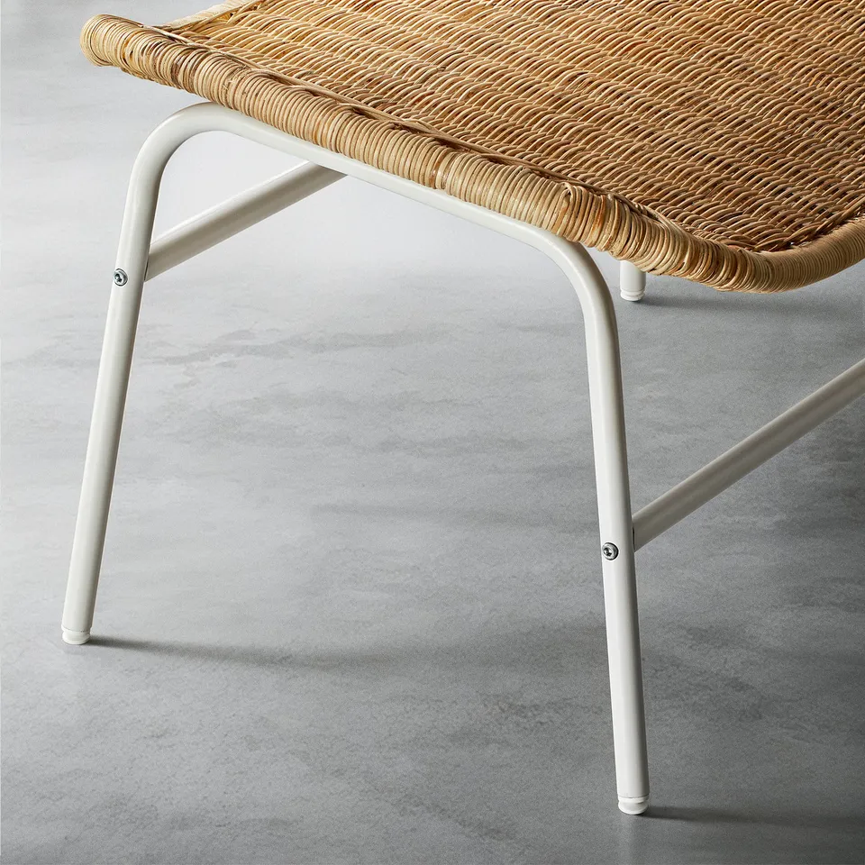Woven rattan footstool with sleek metal legs, showcasing high-quality craftsmanship and natural beauty.