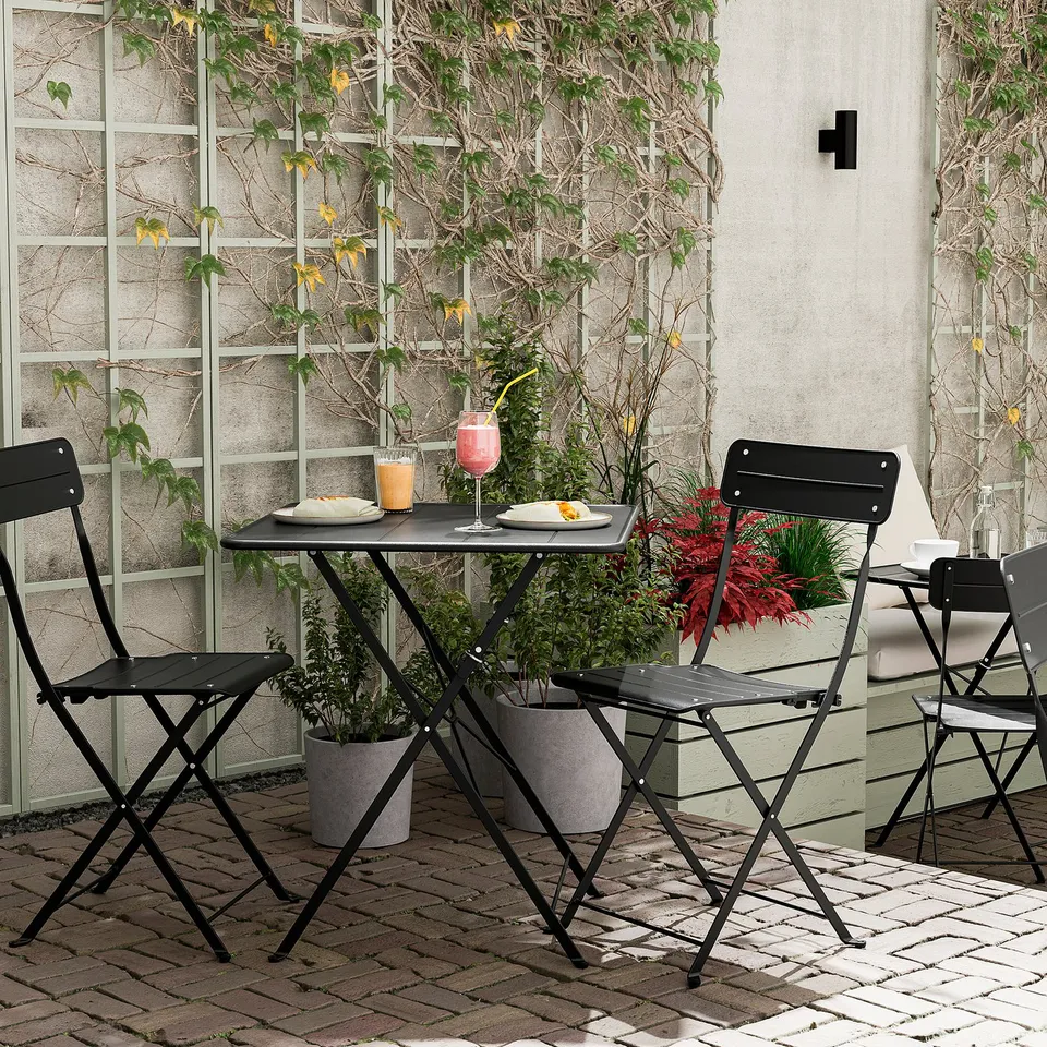 External patio setup with SUNDSÖ black metal table and chairs, potted plants, and drinks.
