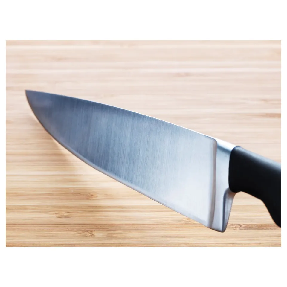 Sharp chefs knife on wooden board, sleek blade, black handle, high-quality design.