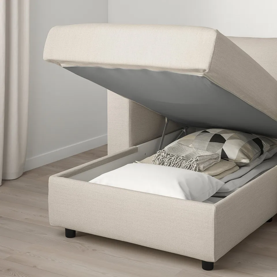Sofa with lift-up storage, blankets inside, light fabric.